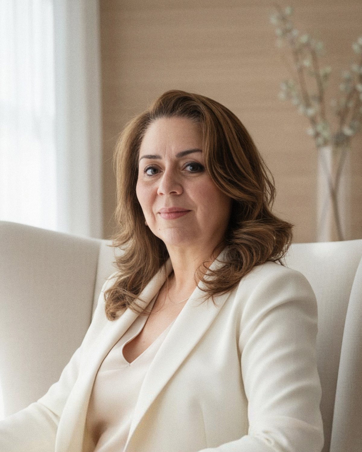 Dra. Edwiges Dias da Rosa sentada em uma poltrona clara, sorrindo